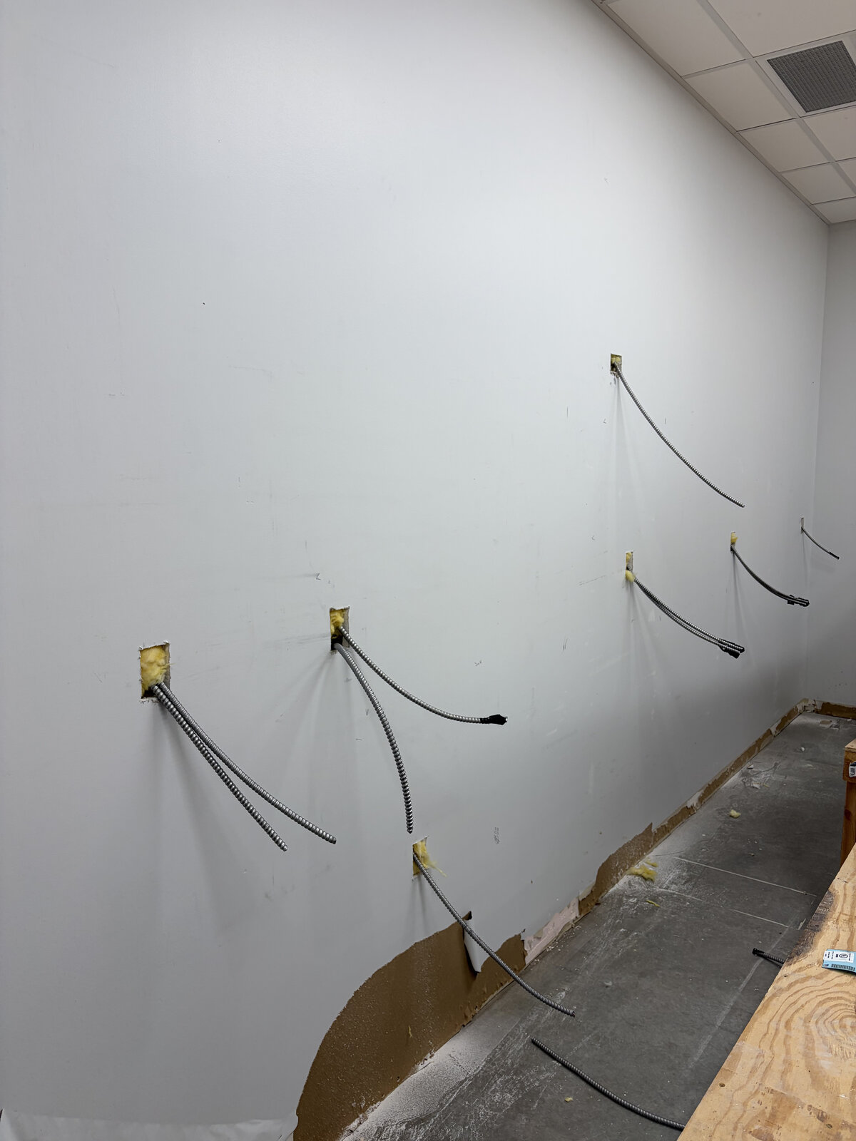 Flexible metal conduits roughed into drywall in a commercial build-out